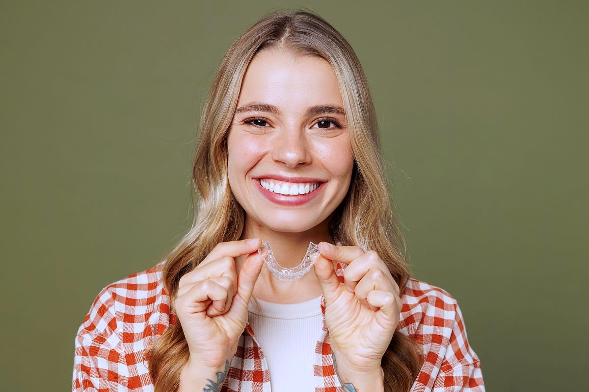 Patient smiling while wearing clear Invisalign aligners