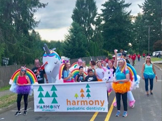 Community parade with colorful unicorn float and participants