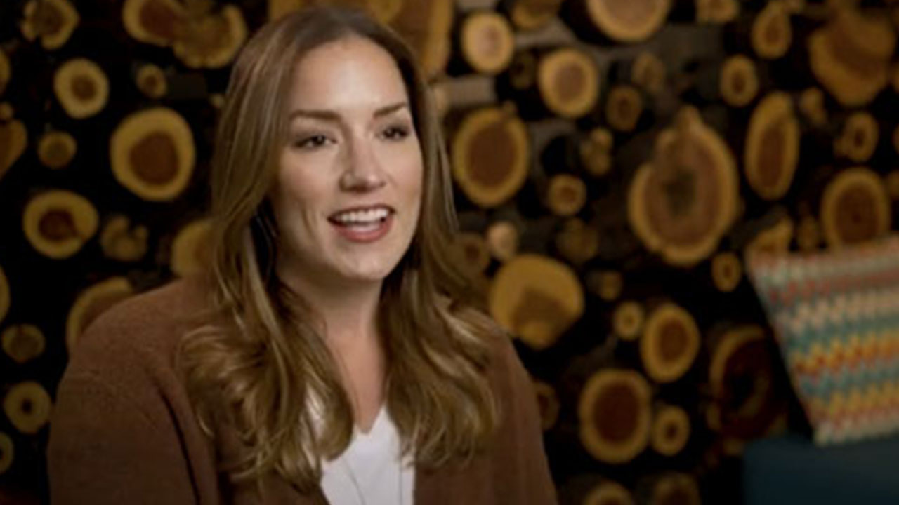 Woman smiling in interview, wood slice background