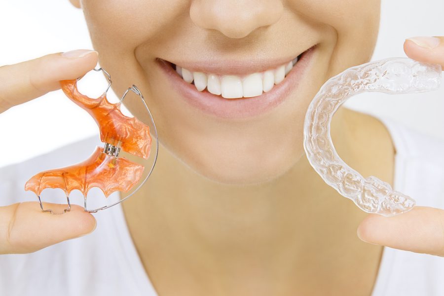 Beautiful smiling girl holding retainer for teeth (dental braces) and individual tooth tray