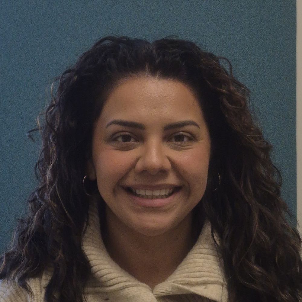Smiling woman with curly hair against a blue background