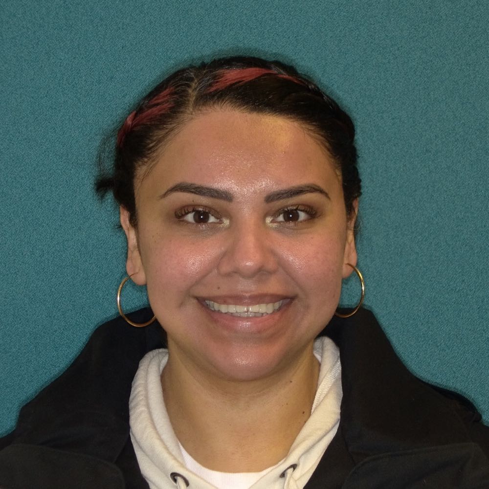 Smiling woman with hoop earrings and pink hair highlights