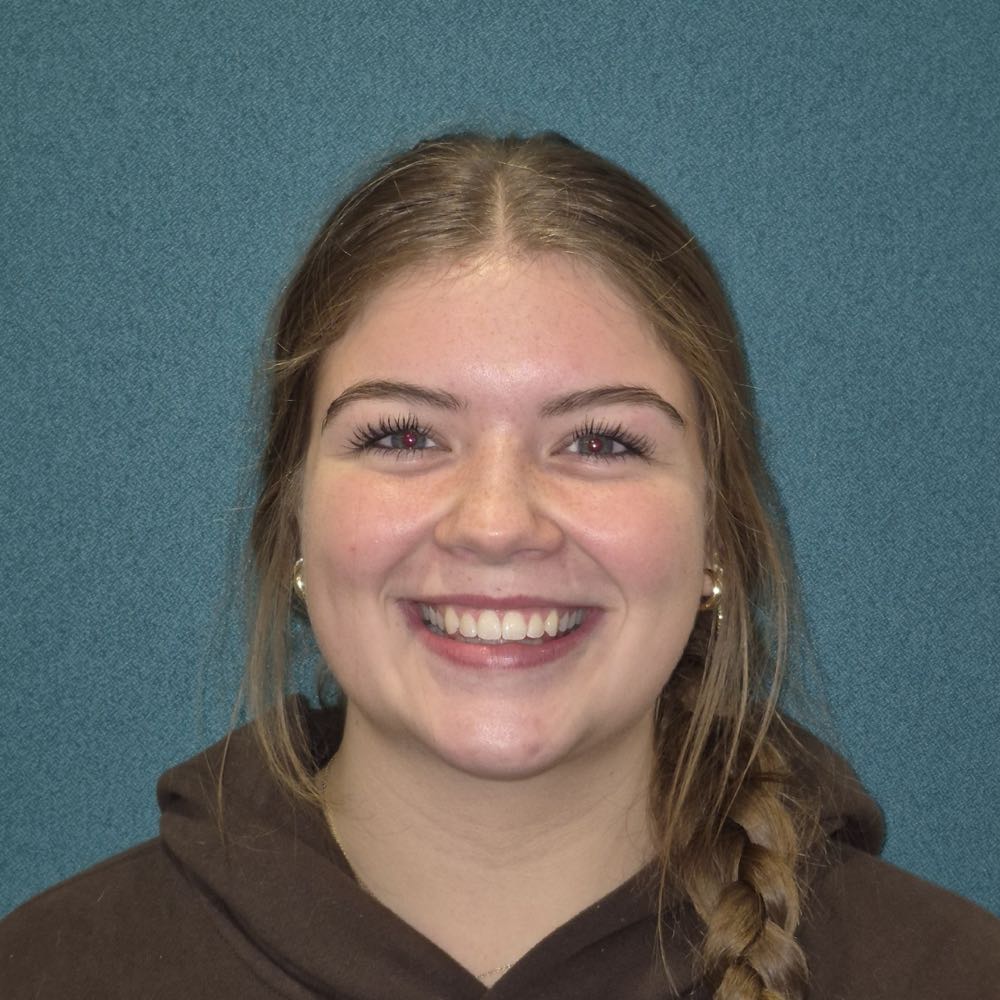 Young woman smiling with braided hair against blue background