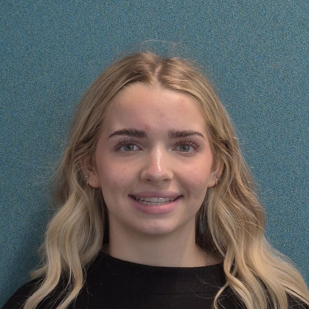 Young blonde woman smiling against turquoise background