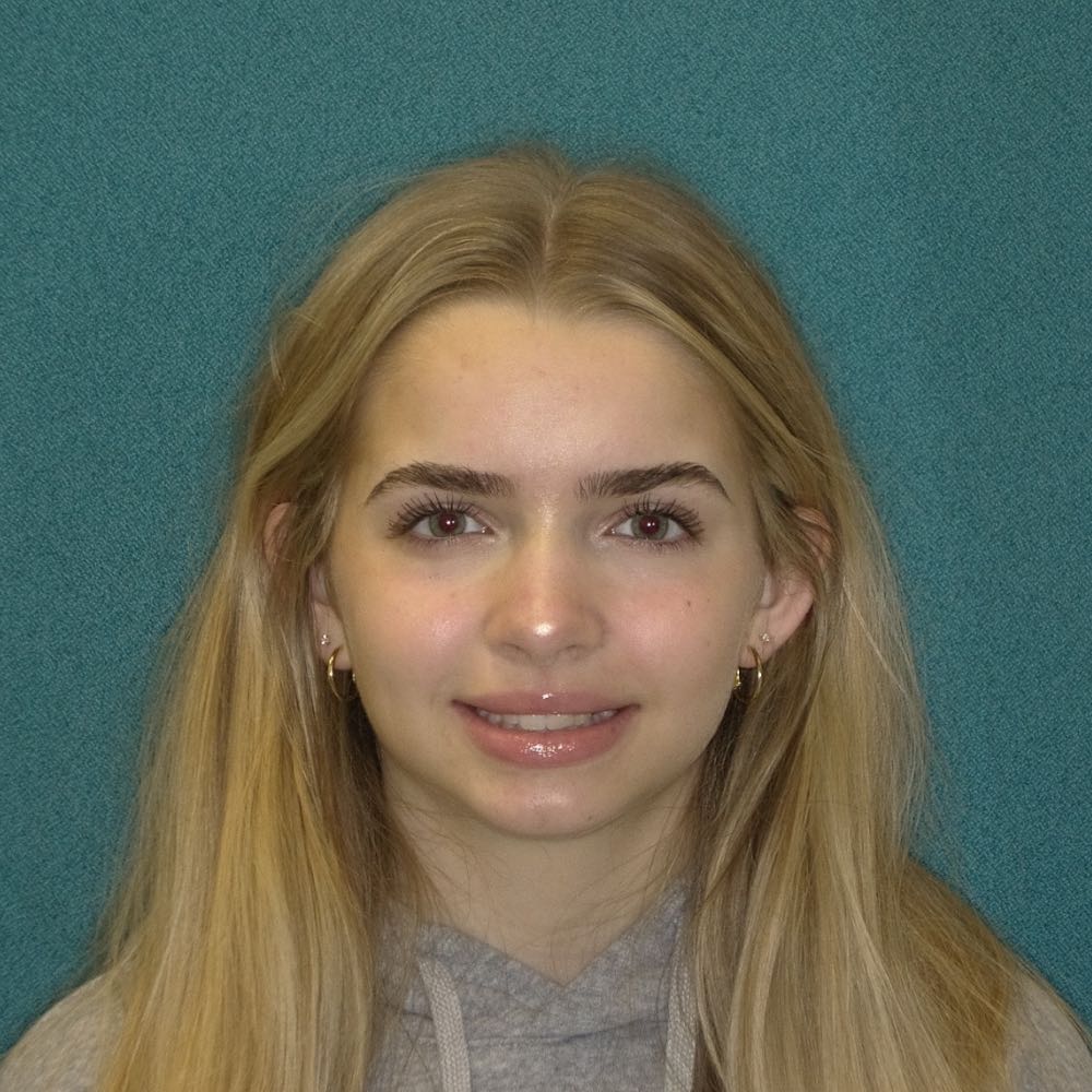 Young woman with blonde hair smiling, teal background