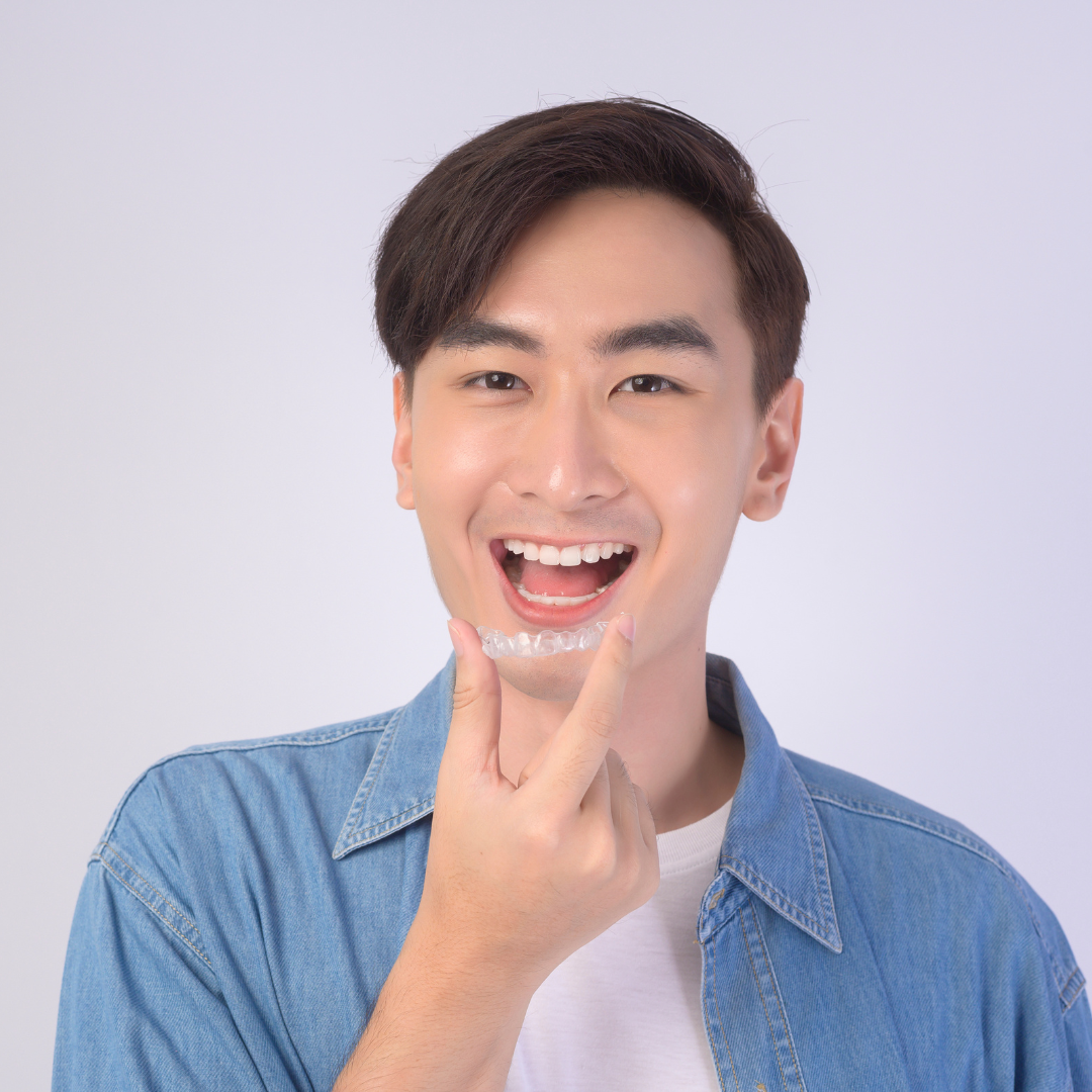 Man smiling pointing at clear orthodontic aligner